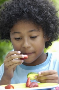 child eating fresh fruits and vegetables