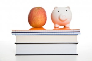 an apple and a piggy bank on top of a stack of books