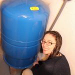 Young woman takes a water sample from a pressure tank